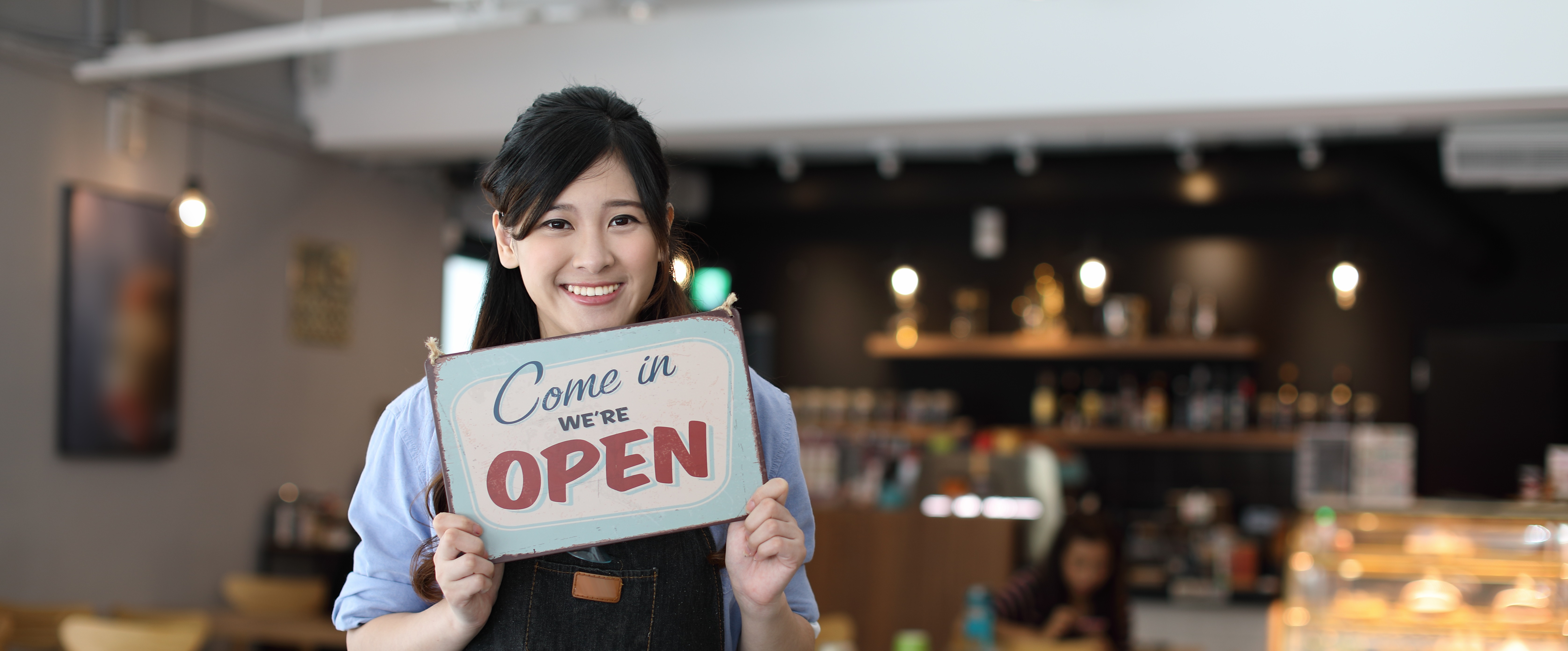 woman holding a sign saying 'we're open'