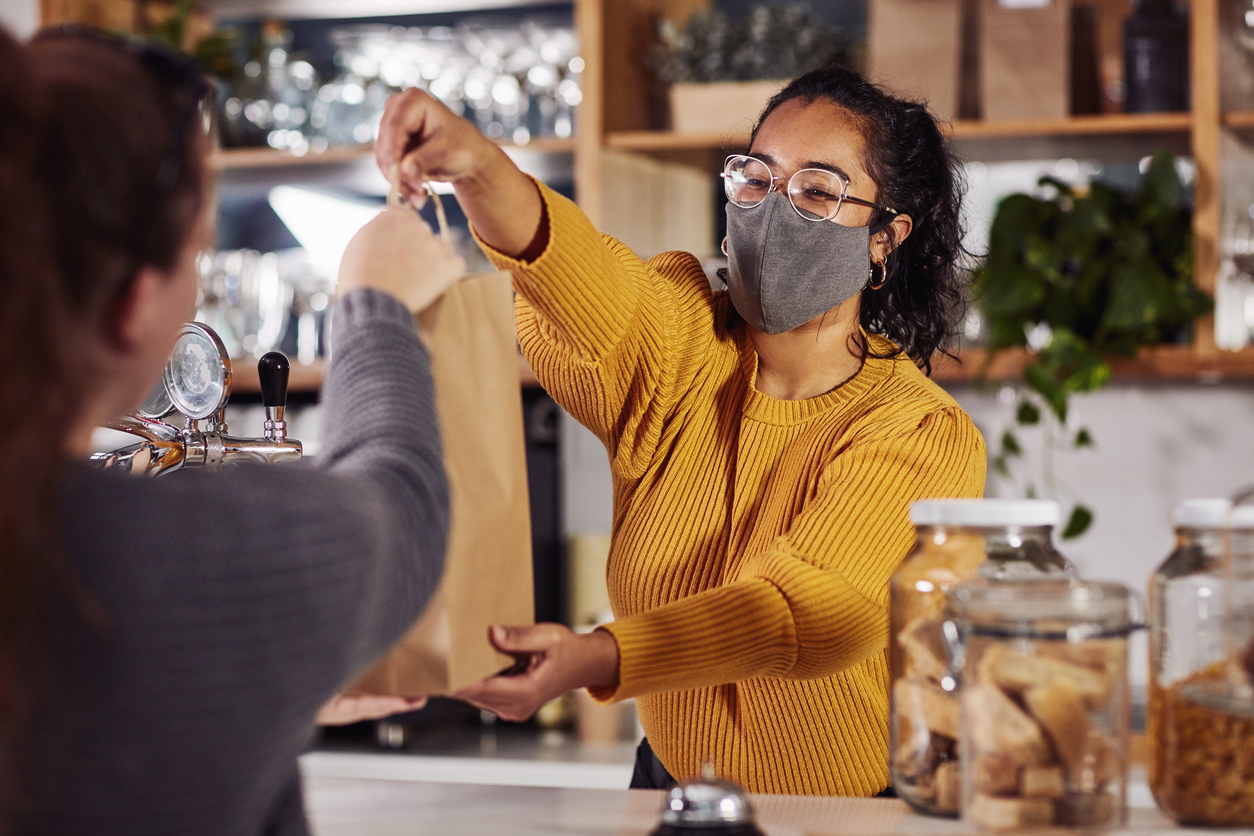 Small business owner handing customer a bag