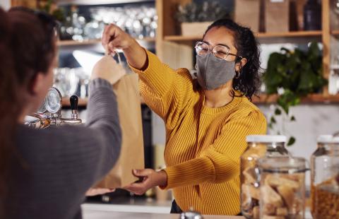 Small business owner handing customer a bag